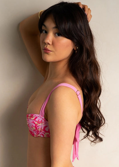 A vibrant, tropical-inspired bikini top. The top is designed with a lively coral background adorned with pastel pink and yellow florals